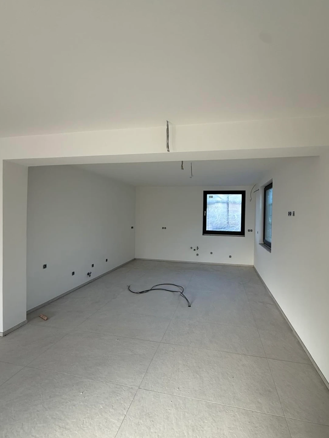 Derselbe Wohnraum fertig: weiße Wände und Decke, helle Bodenfliesen