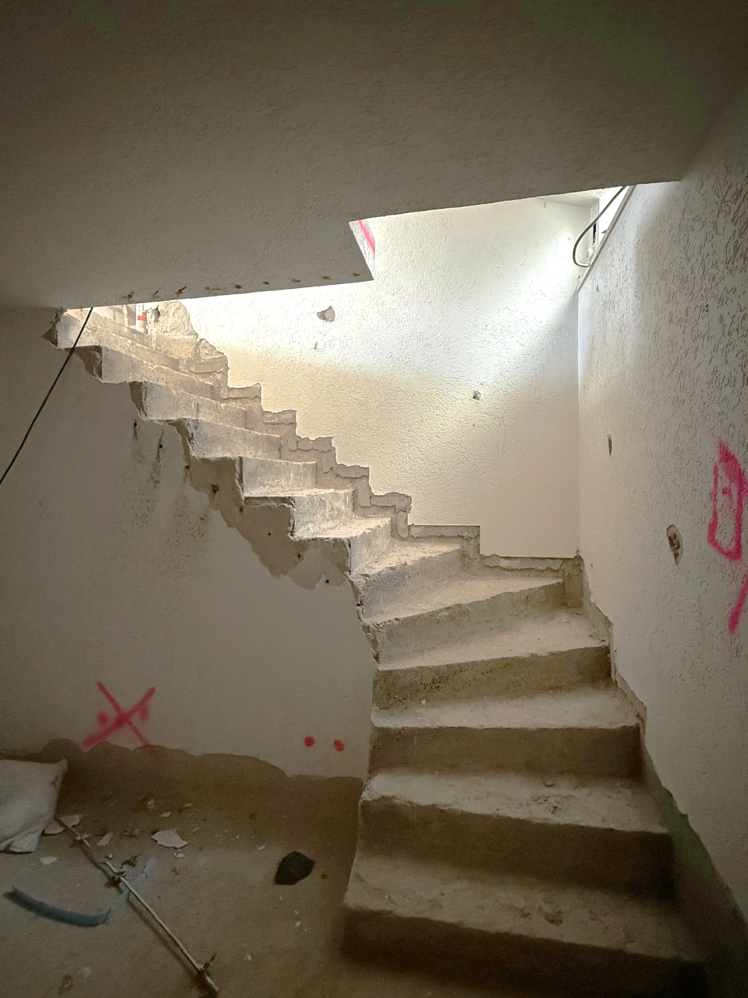Treppenhaus im Rohzustand mit rauen Betonstufen und unverputzten Wänden