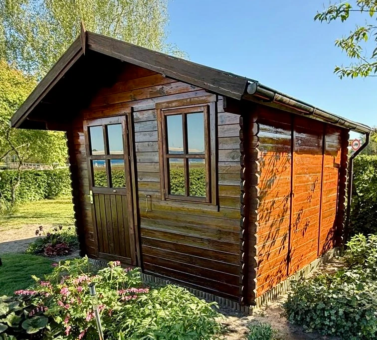 Dasselbe Gartenhaus nach dem Neuanstrich mit frischer, warmer Holzlasur