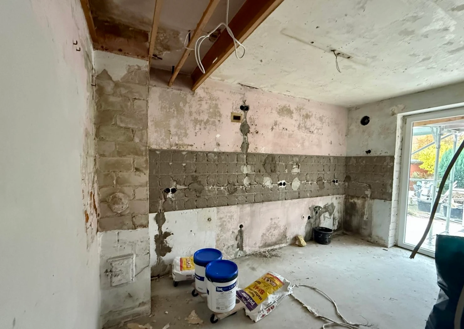 Wohnraum im Rohbau, Putz teilweise abgeschlagen, Mauerwerk sichtbar
